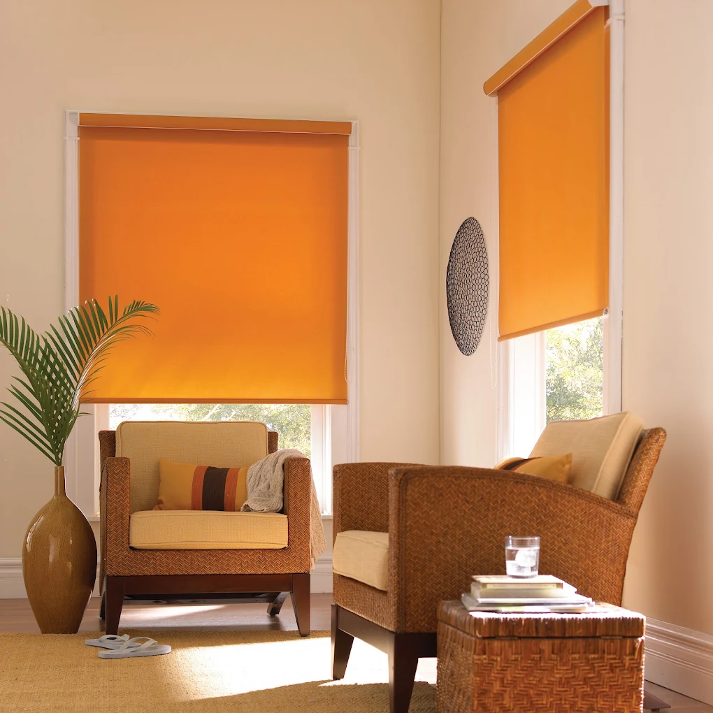 Orange roller blinds in a living room with cane armchairs