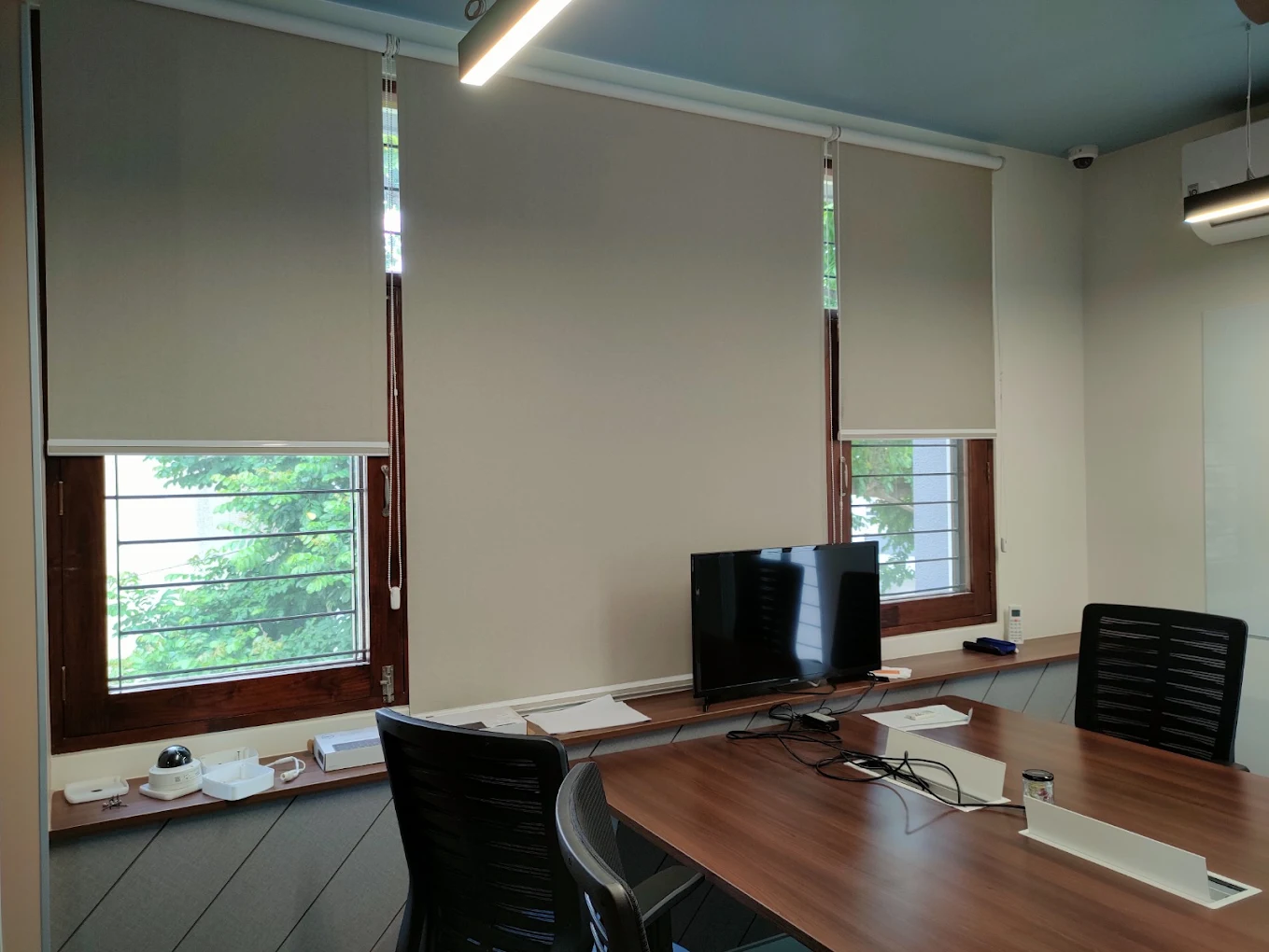 Grey roller blinds half lowered in a conference room